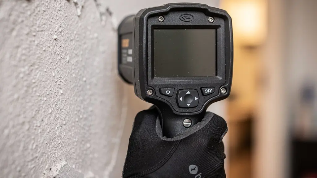 Expert réalisant un diagnostic immobilier dans une maison avec un équipement de mesure.